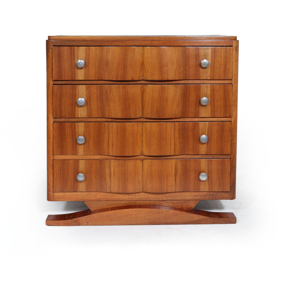 A French Art Deco walnut chest of drawers featuring four wide drawers with silver metal circular handles set on a curved wooden base plinth.