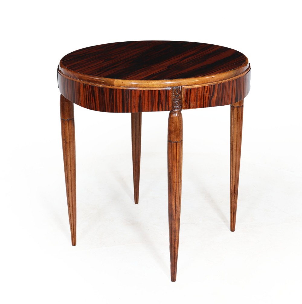 A round French Art Deco side table with a striking Macassar ebony veneer top and circular apron, supported by four slim, fluted walnut legs.