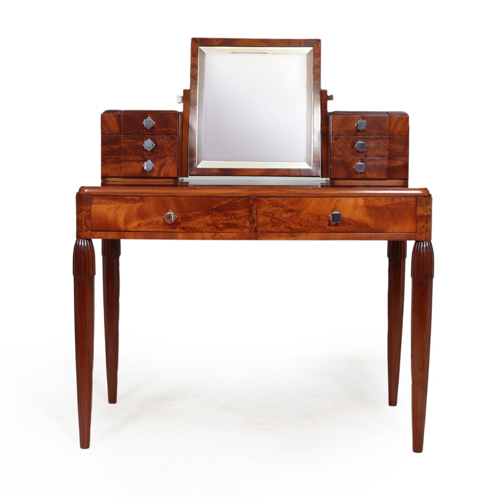 A French Art Deco dressing table crafted from figured walnut with a central rectangular mirror, tiered side drawers, two frieze drawers, and fluted legs.