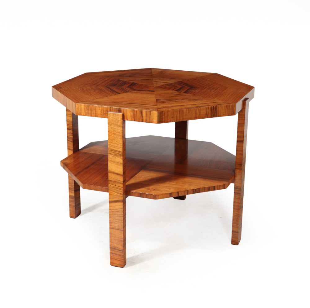 A French Art Deco octagonal walnut coffee table featuring a bookmatched veneer top, lower tier shelf, and four straight legs.