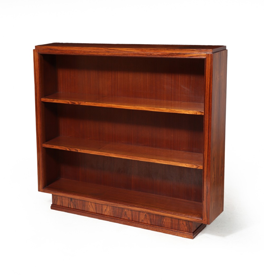 A low French Art Deco open bookcase crafted from richly grained rosewood featuring a stepped rectangular frame and two open shelves resting on a plinth base.