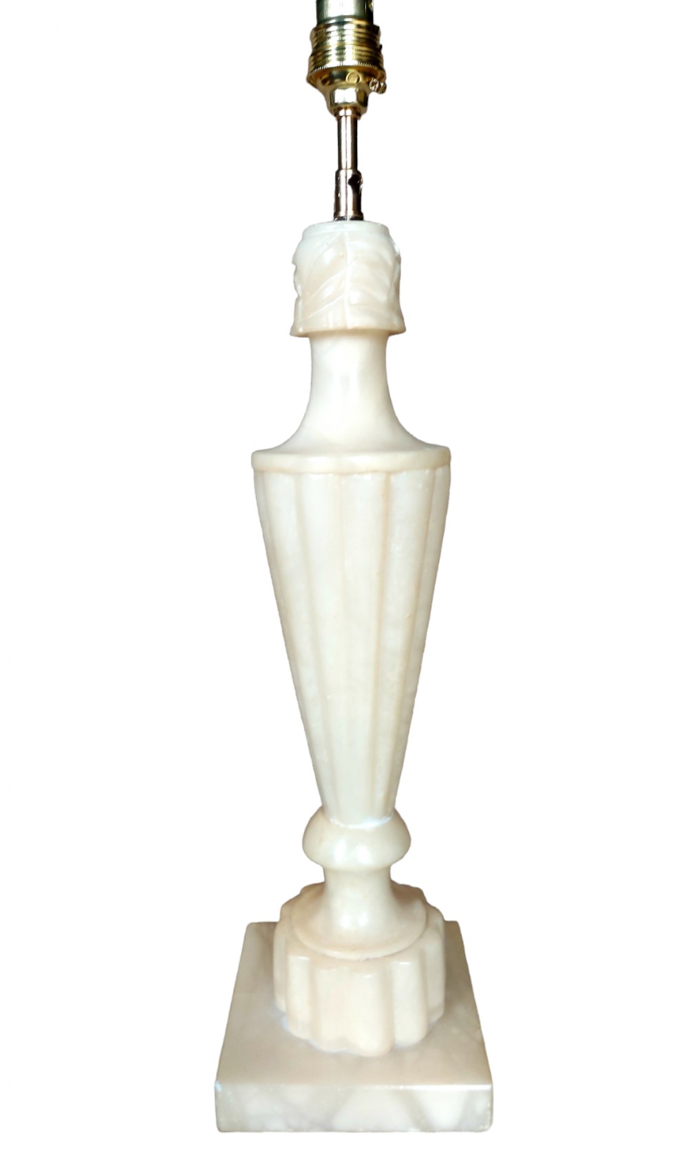 A carved cream alabaster table lamp base featuring fluted urn shaping set upon a square stepped pedestal with a brass socket.