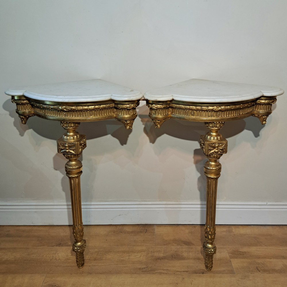 A pair of nineteenth-century French Neoclassical giltwood corner console tables with white marble tops and fluted single legs. View V