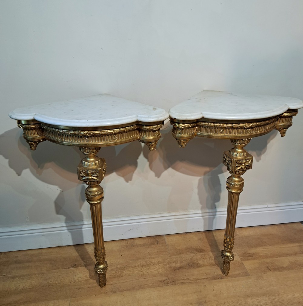A pair of nineteenth-century French Neoclassical giltwood corner console tables with white marble tops and fluted single legs. View VI