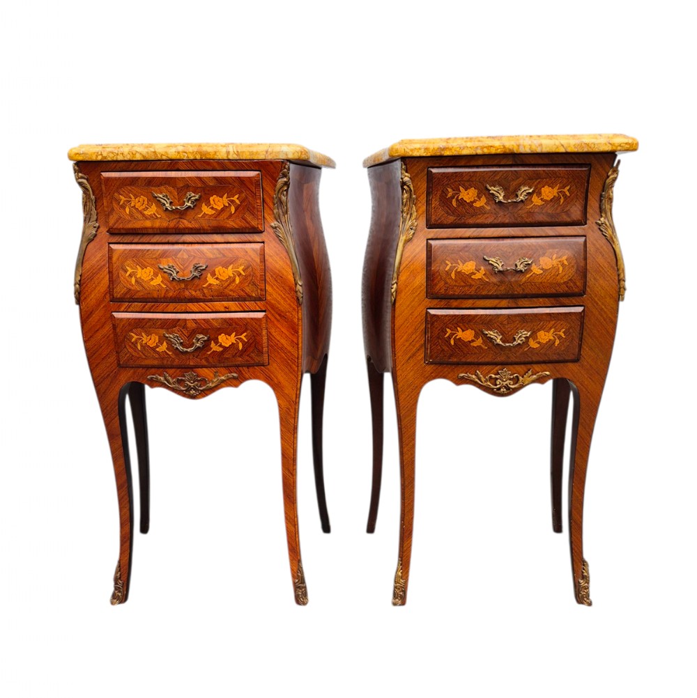A pair of French Louis XV style bombe bedside cabinets featuring warm brown wood veneer with floral marquetry inlays, gold-toned metal drawer handles, slender cabriole legs, and yellow marble tops.