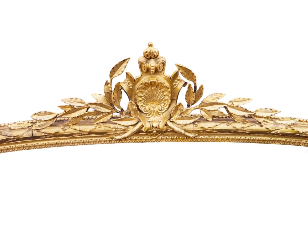 A large 19th-century gold giltwood overmantel mirror featuring an arched top with a carved central shell crest. View II