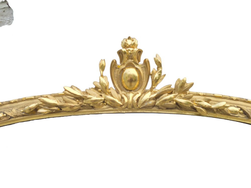 A large arched 19th-century gold giltwood overmantel mirror featuring a top foliage crest, beaded inner moulding, and scrolled side flourishes. View III