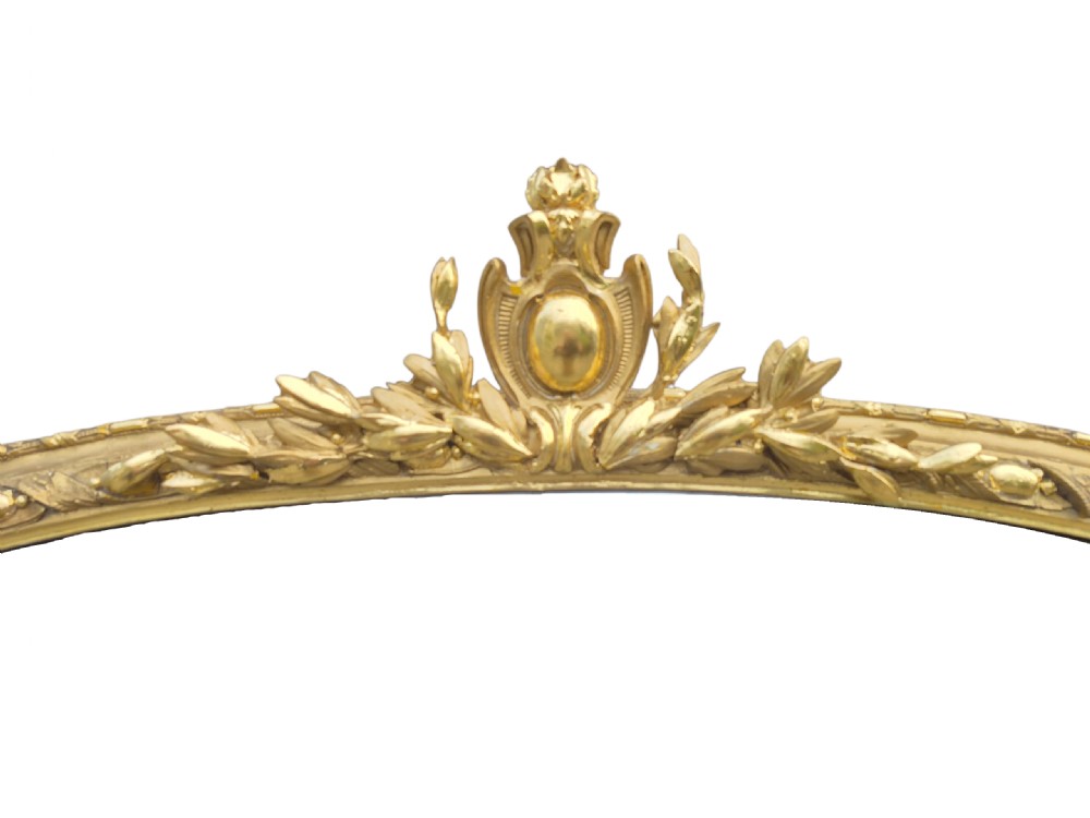 A large arched 19th-century gold giltwood overmantel mirror featuring a top foliage crest, beaded inner moulding, and scrolled side flourishes. View VIII