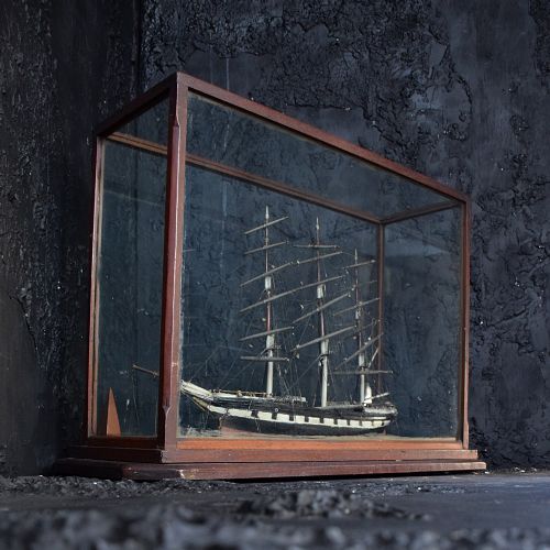 fig 1. A detailed three-masted wooden model sailing ship with intricate rigging enclosed inside a glazed rectangular dark wood case.