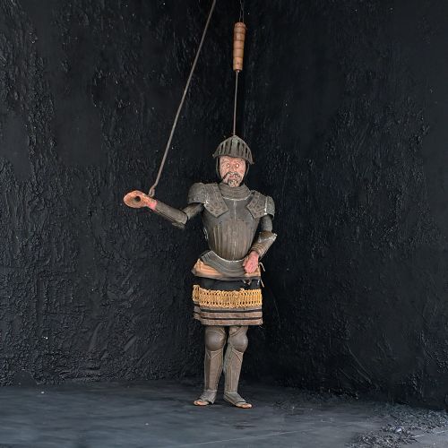 fig 1. A mid-19th century Sicilian marionette figure featuring articulated iron body armour, a carved wooden head, and layered fabric garments suspended by a upper iron rod.