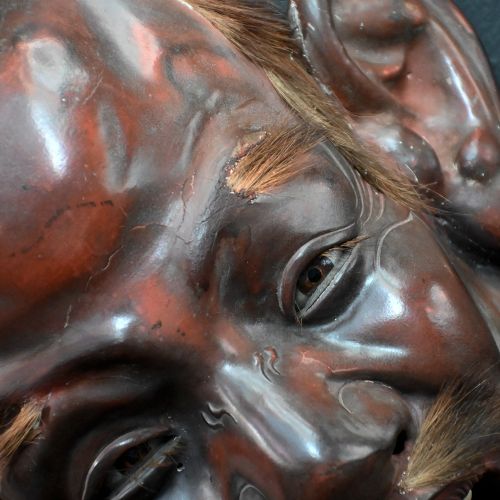fig 3. A 19th-century carved wooden Japanese mask with a grimacing open mouth, exaggerated ears, applied hair details, and a dark lacquered finish.
