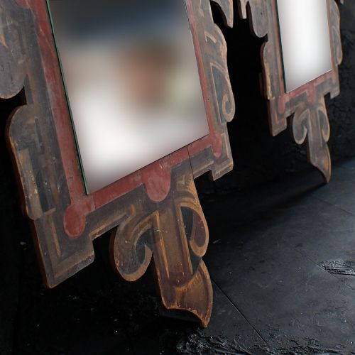 fig 2. A pair of early twentieth-century fairground mirrors with carved scrollwork borders painted in gold and red tones around central rectangular mirror panels.
