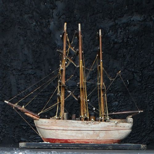 fig 1. An early 20th-century scratch-built wooden three-masted sailing ship model mounted on a textured green sea base inside a dark timber frame.
