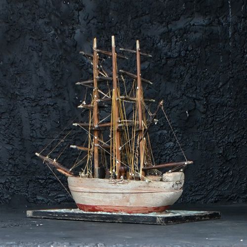 fig 2. An early 20th-century scratch-built wooden three-masted sailing ship model mounted on a textured green sea base inside a dark timber frame.