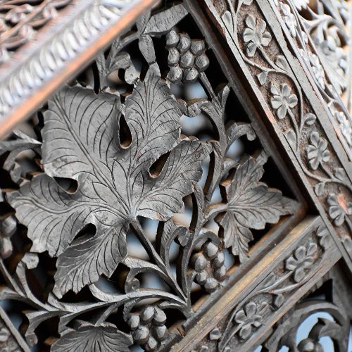 fig 2. An octagonal 19th-century Anglo-Indian side table featuring detailed pierced vine and leaf carvings on a dark wood folding base.