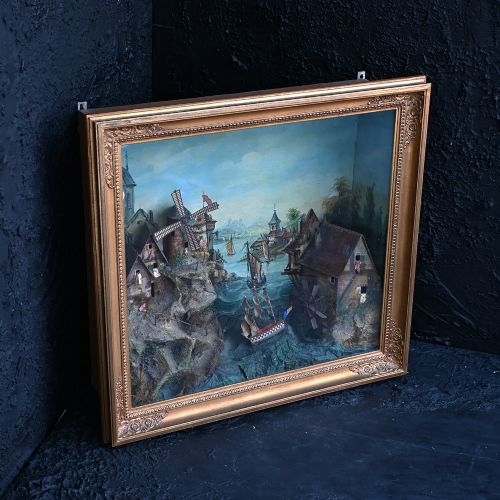fig 2. A nineteenth-century framed picture clock shadowbox featuring a painted coastal village scene with a windmill, clock tower, and sailing vessels inside a gilt frame.