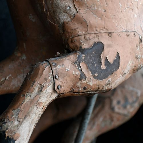 fig 2. A pair of 19th-century carved wooden carousel pigs with distressed pink paint mounted on slender iron display stands.