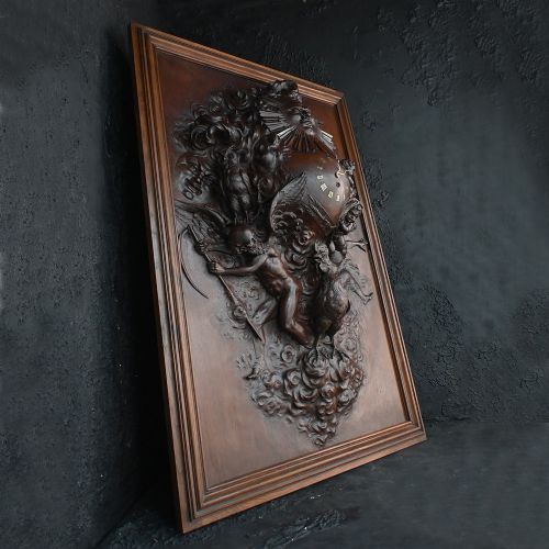 fig 6. A rectangular dark wood carved panel featuring a central heart-shaped clock face surrounded by allegorical figures, a sun motif, and clouds within a moulded wooden frame.