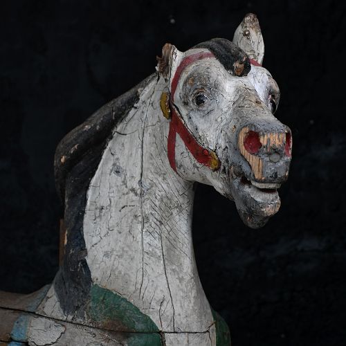 fig 2. A 19th-century French carved wooden carousel horse with distressed white, red, green, and blue paint in a galloping pose.