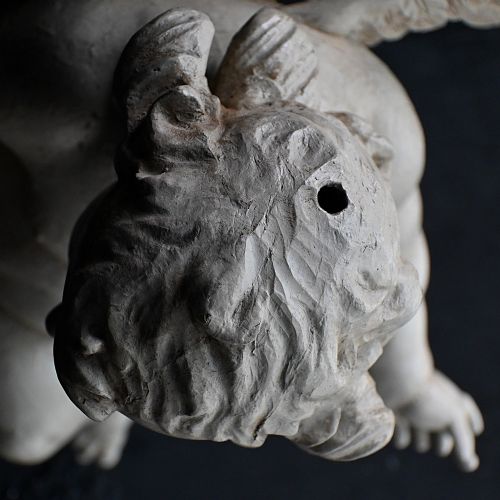 fig 1. A late 18th-century hand-carved wooden cherub figure with outstretched arms, detailed wings, and a painted grey finish.