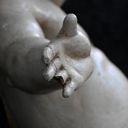 fig 3. A late 18th-century hand-carved wooden cherub figure with outstretched arms, detailed wings, and a painted grey finish.