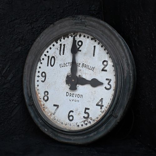 fig 1. An oversized circular French station wall clock featuring a dark grey metal bezel, off-white dial with Arabic numerals, and French maker inscriptions.