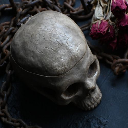 fig 1. A hand-carved wooden skull sculpture displaying carved teeth and eye sockets with an aged brown patina.