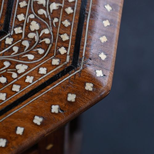 fig 4. An early 20th-century octagonal wooden occasional table featuring intricate bone inlay floral and geometric patterns across the top and arched apron base.