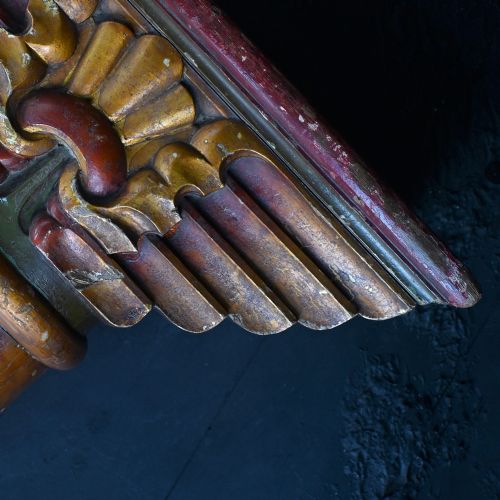 fig 3. A matched pair of early 20th-century tall wooden fairground carousel columns featuring flared carved capitals, faux-marble painted shafts with winged motifs, and dark green square plinths.