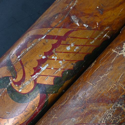 fig 8. A matched pair of early 20th-century tall wooden fairground carousel columns featuring flared carved capitals, faux-marble painted shafts with winged motifs, and dark green square plinths.
