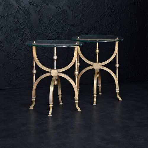 fig 2. A pair of aged brass side tables featuring curule-shaped X-frames, turned central spindles, and circular clear glass tops.