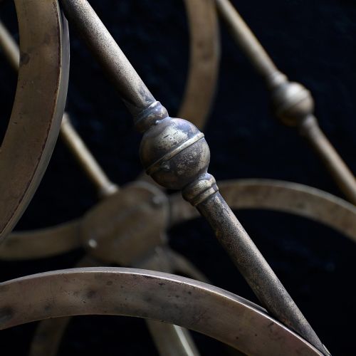 fig 4. A pair of aged brass side tables featuring curule-shaped X-frames, turned central spindles, and circular clear glass tops.