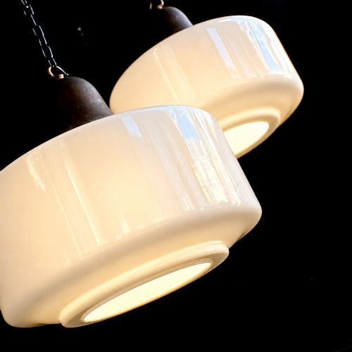 fig 1. A matched pair of Art Deco pendant lights featuring large white opal glass shades topped with bell-shaped copper galleries and hanging chains.