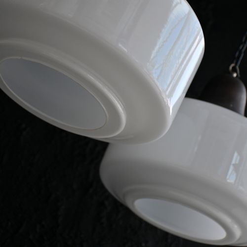 fig 4. A matched pair of Art Deco pendant lights featuring large white opal glass shades topped with bell-shaped copper galleries and hanging chains.