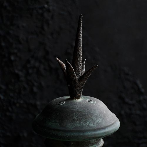 fig 2. A nineteenth-century copper wall lantern with glazed panels, a tapered rectangular body, and a decorative finial on top.