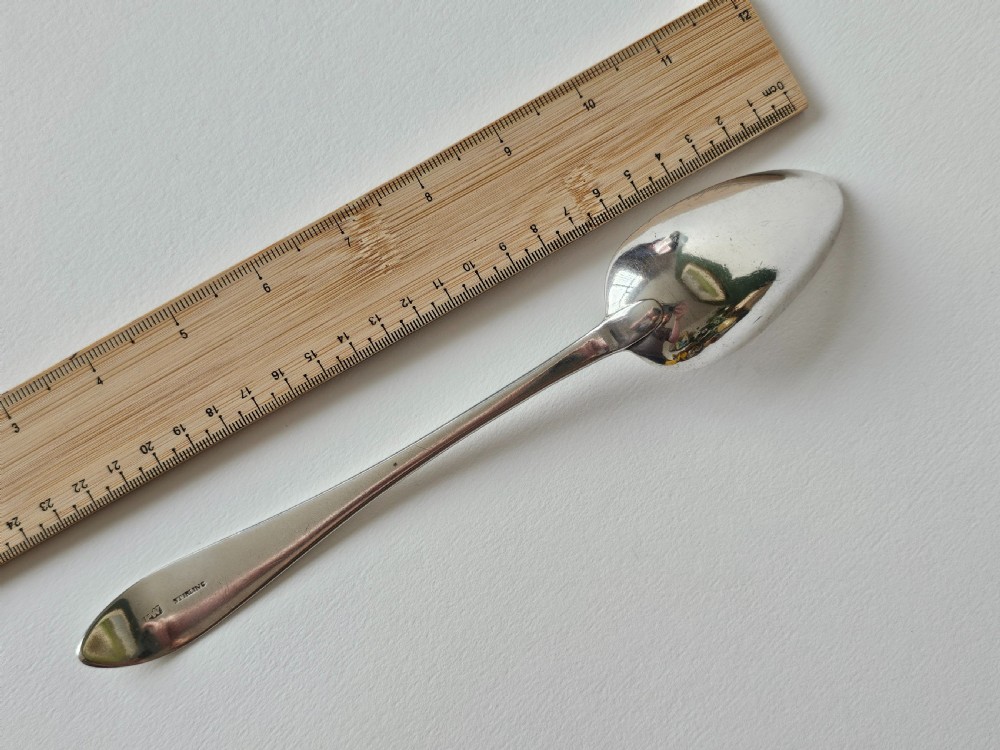 An antique Irish Georgian silver spoon featuring an elongated oval bowl and engraved detailing along the terminal. View IV