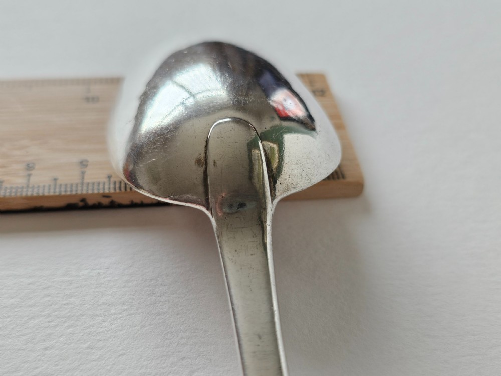 An antique Irish Georgian silver spoon featuring an elongated oval bowl and engraved detailing along the terminal. View V