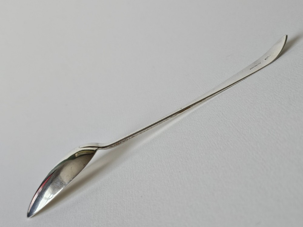 An antique Irish Georgian silver spoon featuring an elongated oval bowl and engraved detailing along the terminal. View VI