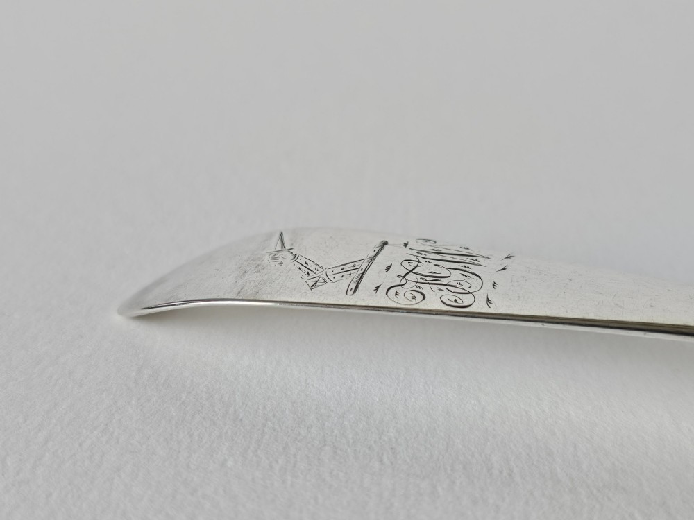 An antique Irish Georgian silver spoon featuring an elongated oval bowl and engraved detailing along the terminal. View IX