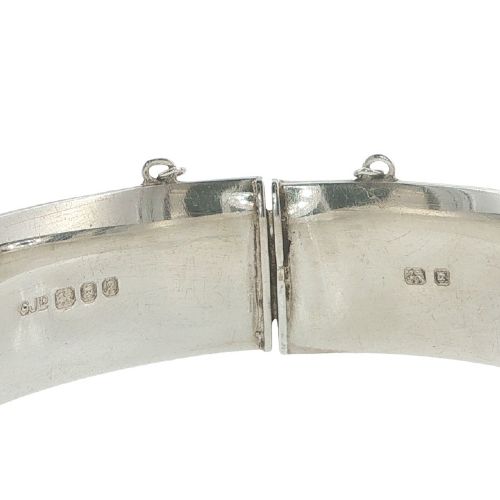 fig 3. A sterling silver hinged bangle featuring floral hand engraving around the exterior band and an attached safety chain.