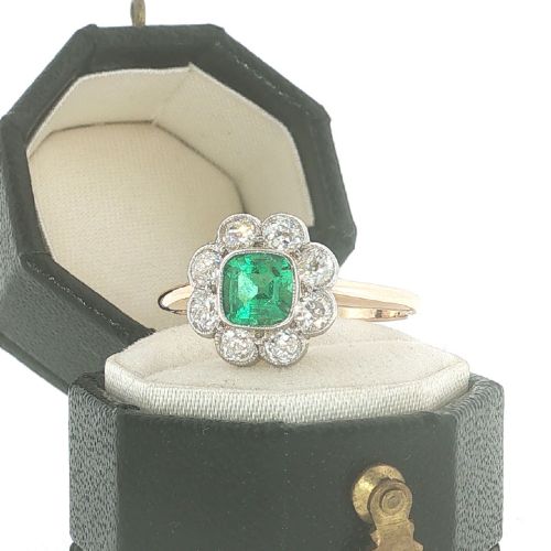 An antique 18ct yellow gold ring featuring a central square green emerald surrounded by a scalloped cluster of diamonds. View V