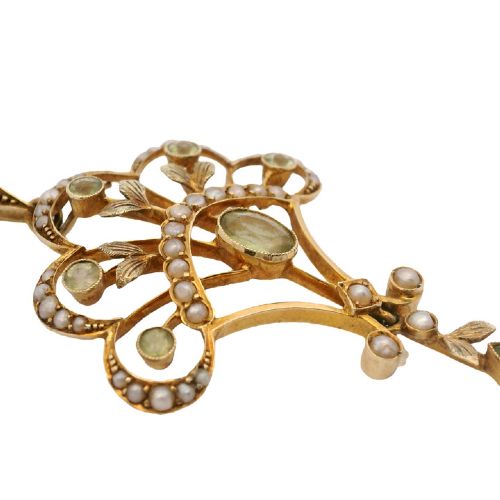 fig 1. An openwork 15ct yellow gold Edwardian pendant set with small seed pearls and light green peridot gemstones with a central oval stone and hanging drop.