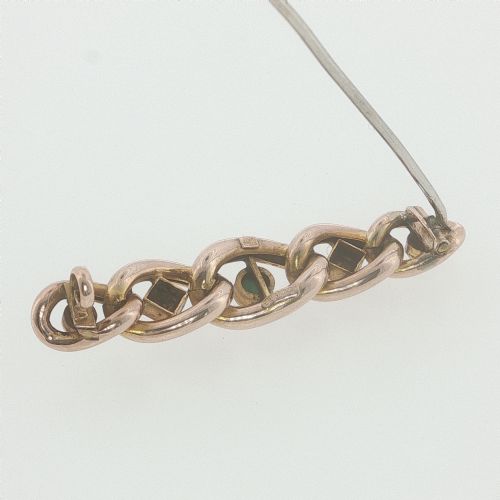 fig 3. An antique 9ct rose gold bar brooch with curb links set with turquoise cabochons and seed pearls resting in a fitted presentation box.