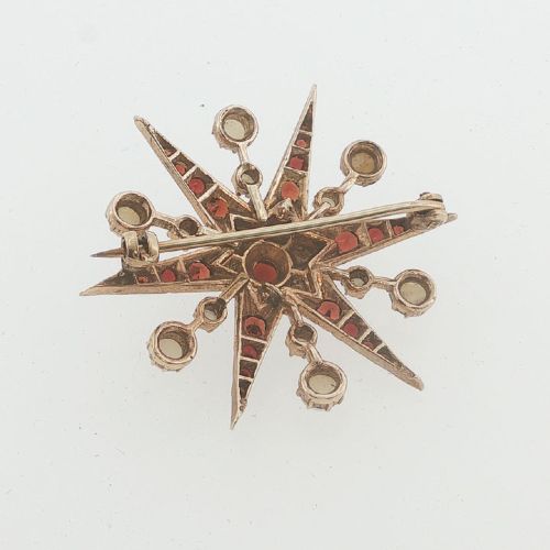 fig 1. A 9ct yellow gold starburst brooch set with a central round garnet, surrounded by radiating point rays set with smaller garnets and seed pearls.