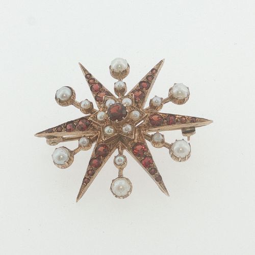 fig 2. A 9ct yellow gold starburst brooch set with a central round garnet, surrounded by radiating point rays set with smaller garnets and seed pearls.