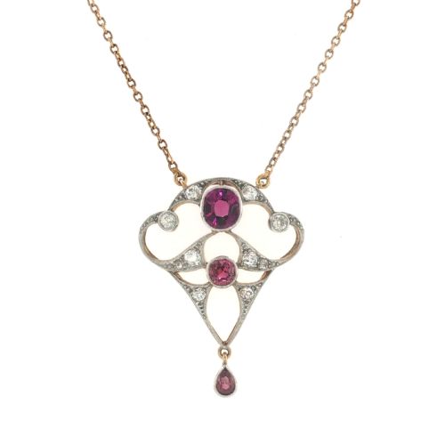 fig 1. An Edwardian openwork 15ct gold and silver-topped pendant set with round rubies, diamond accents, and a pear-cut ruby drop on a gold chain.