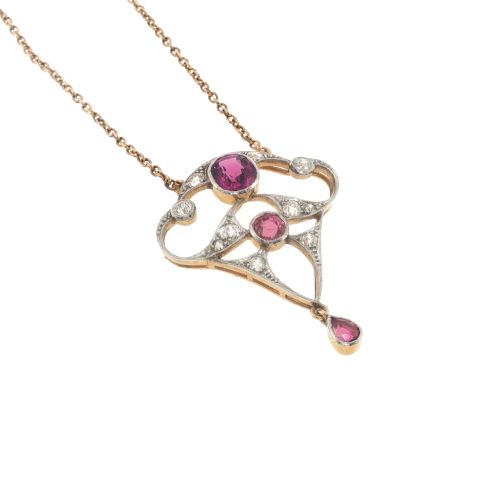 fig 2. An Edwardian openwork 15ct gold and silver-topped pendant set with round rubies, diamond accents, and a pear-cut ruby drop on a gold chain.