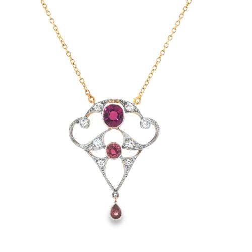 fig 4. An Edwardian openwork 15ct gold and silver-topped pendant set with round rubies, diamond accents, and a pear-cut ruby drop on a gold chain.