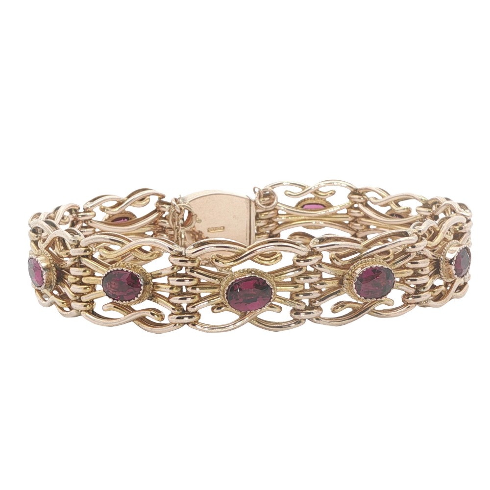 An Edwardian 9ct rose gold link bracelet featuring openwork scroll links set with oval cut almandine garnets.