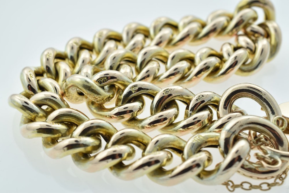 An antique 9ct gold curb link bracelet featuring half-engraved links, a heart-shaped padlock clasp, and an attached safety chain. View VI